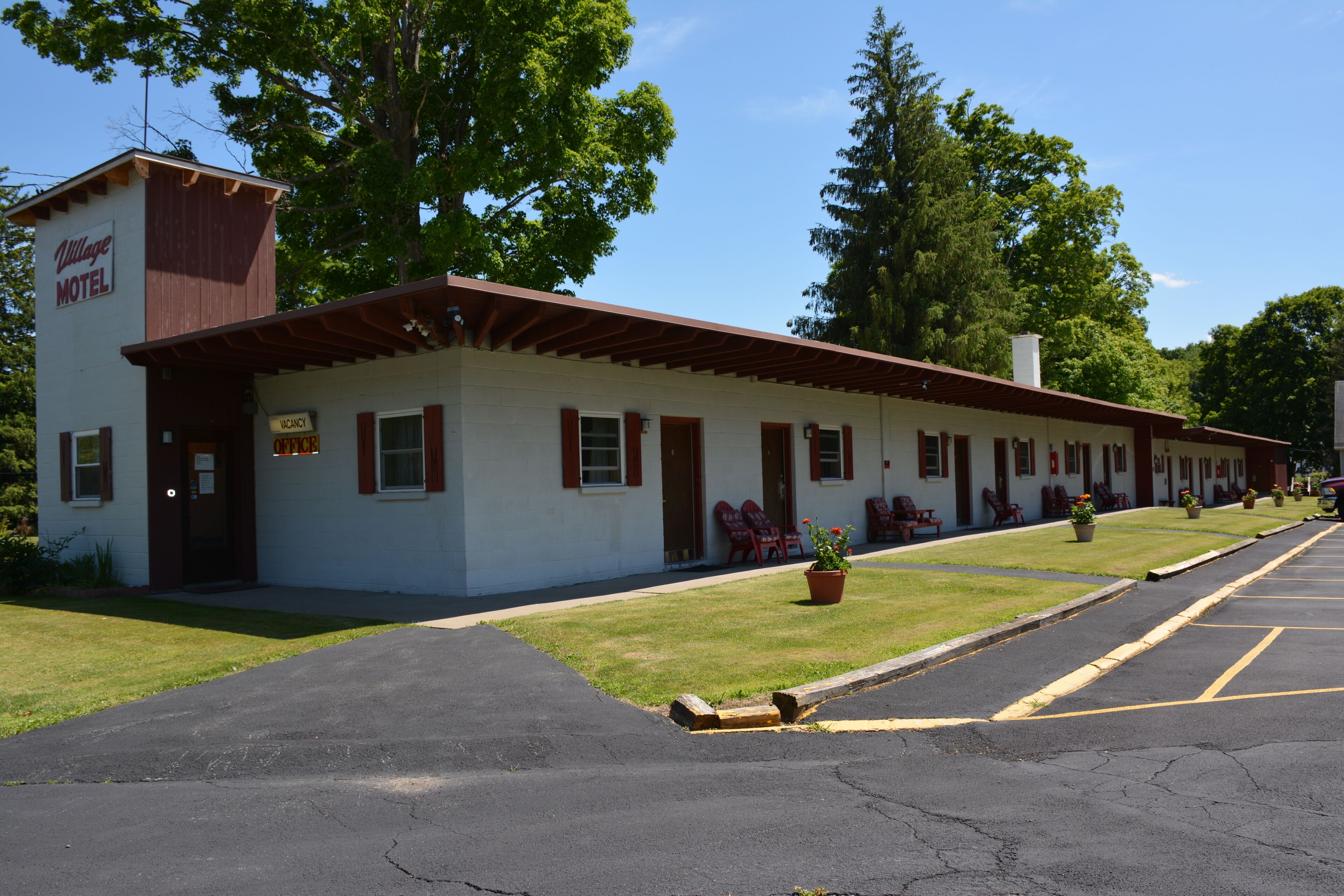 A motel with a single-story structure, a front porch, and a parking lot.