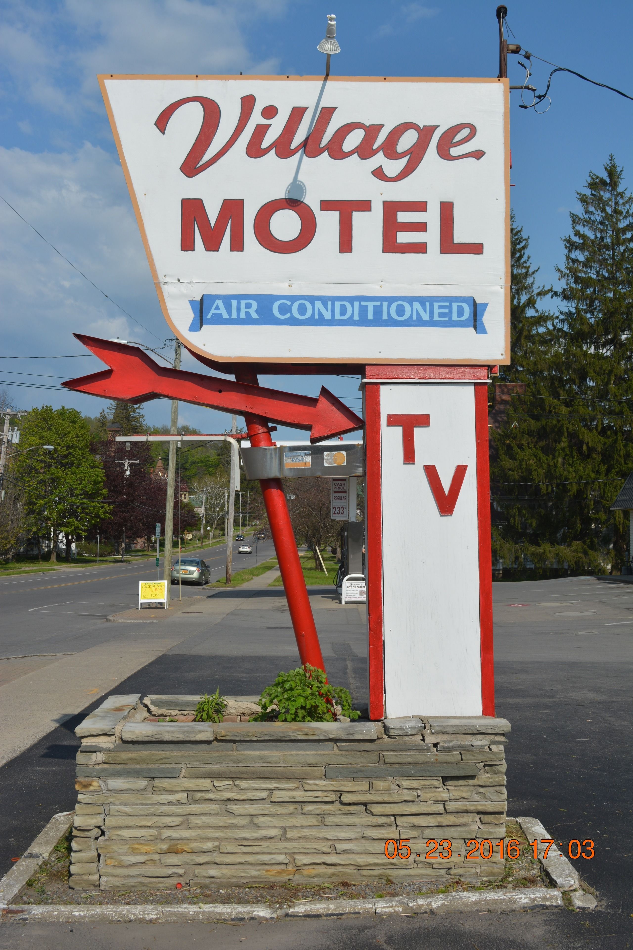 A Village Motel sign with arrows indicating directions and a TV symbol.