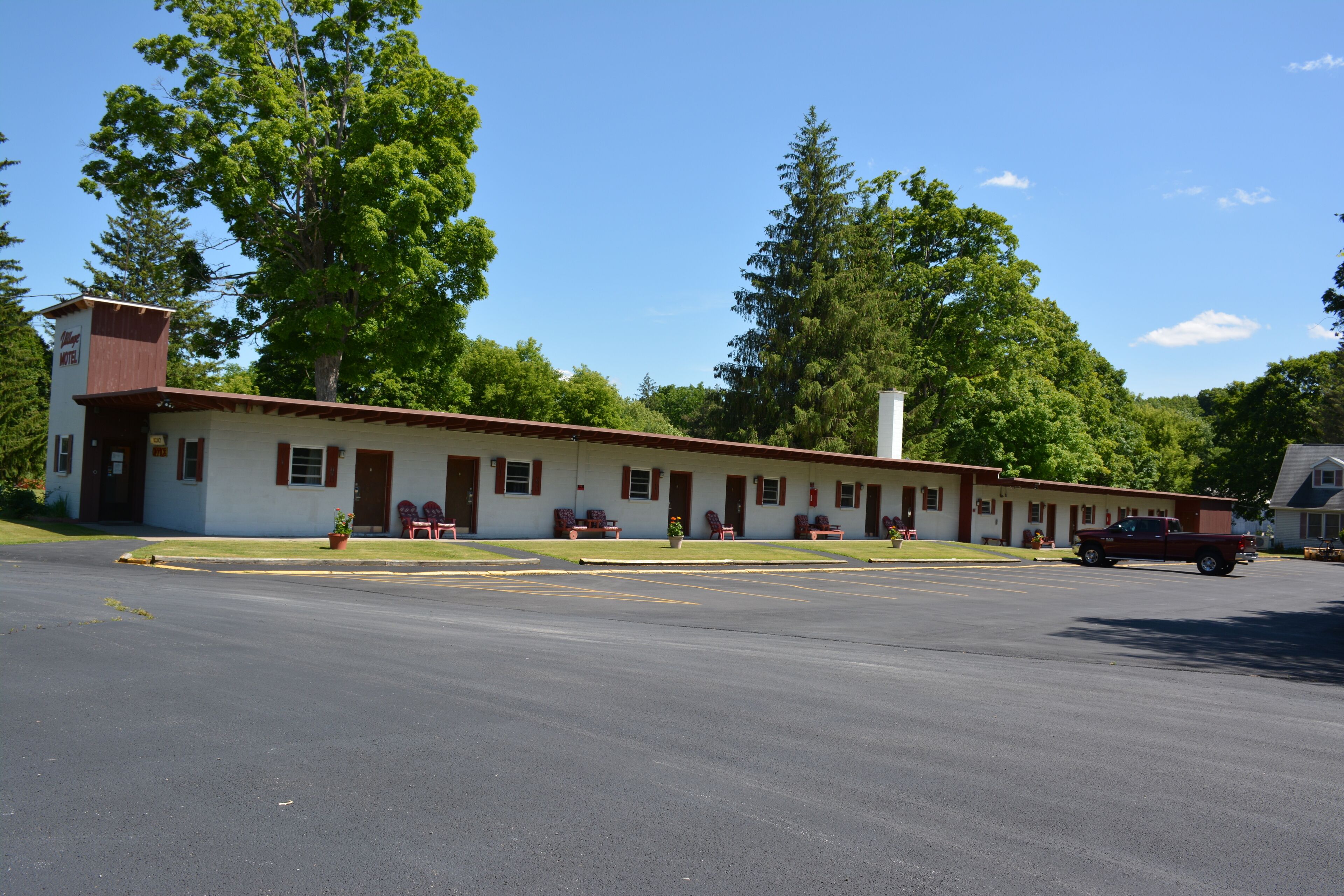 Un motel avec une rangée de chambres, un parking et un camion garé devant.