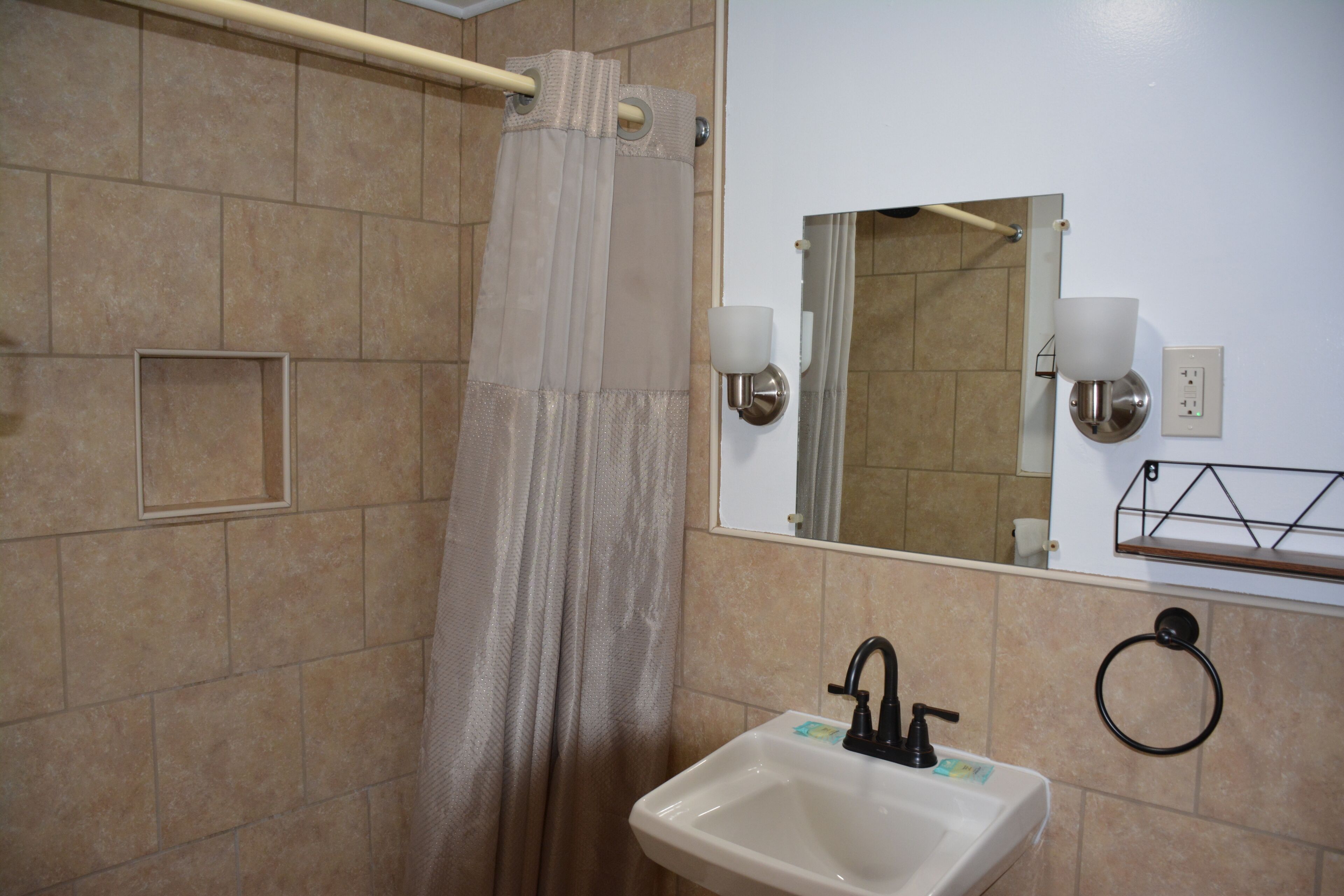 A bathroom with a shower, a sink, a mirror, and a towel ring.