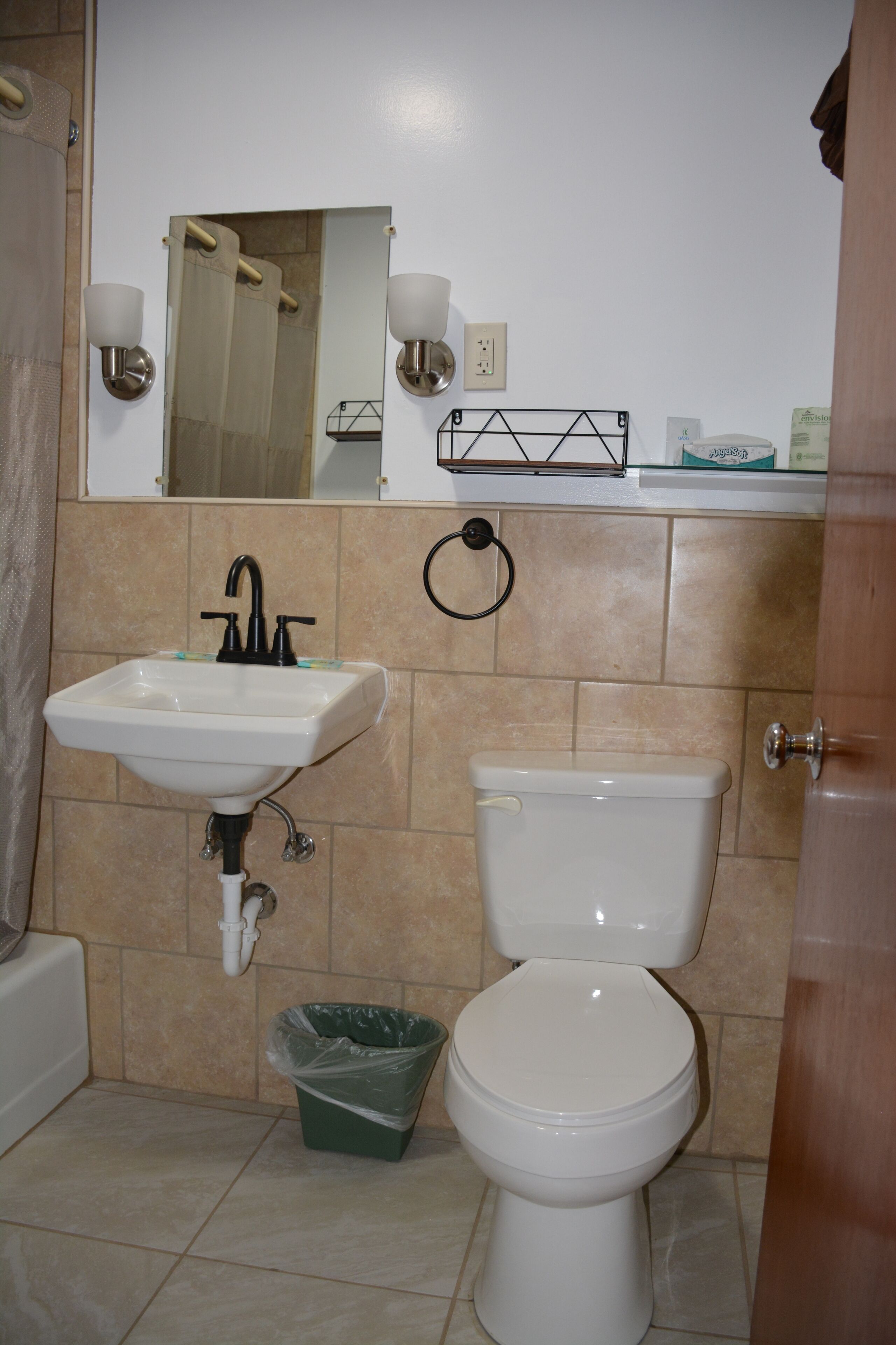 A bathroom with a sink, toilet, and mirror.