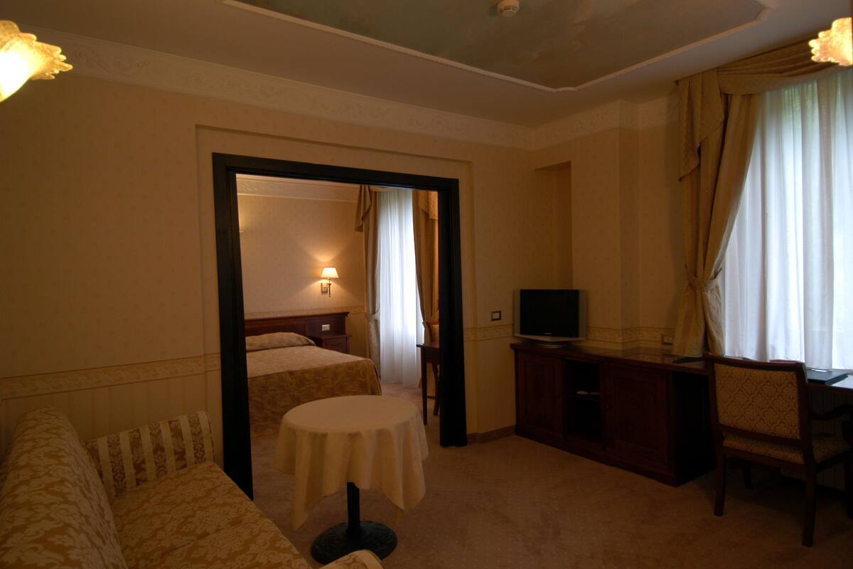 Una habitación de hotel con una cama, un escritorio, un televisor y una mesita redonda.