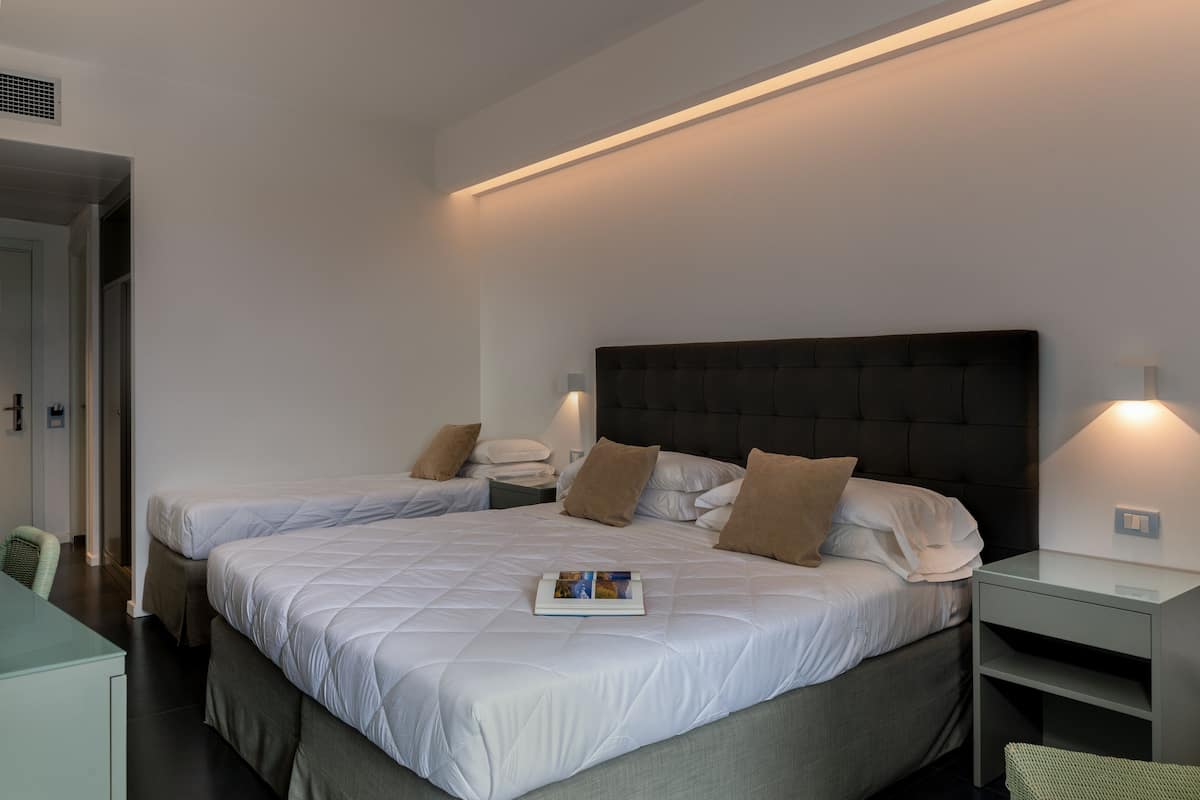 A hotel room with two beds, a desk, and a chair.