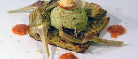 A dish with artichoke hearts, green puree, and sauce on a white plate.
