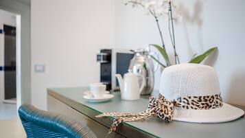 Un cappello bianco con fascia a stampa leopardo su un tavolo di vetro, una teiera bianca e una tazza su un piattino.