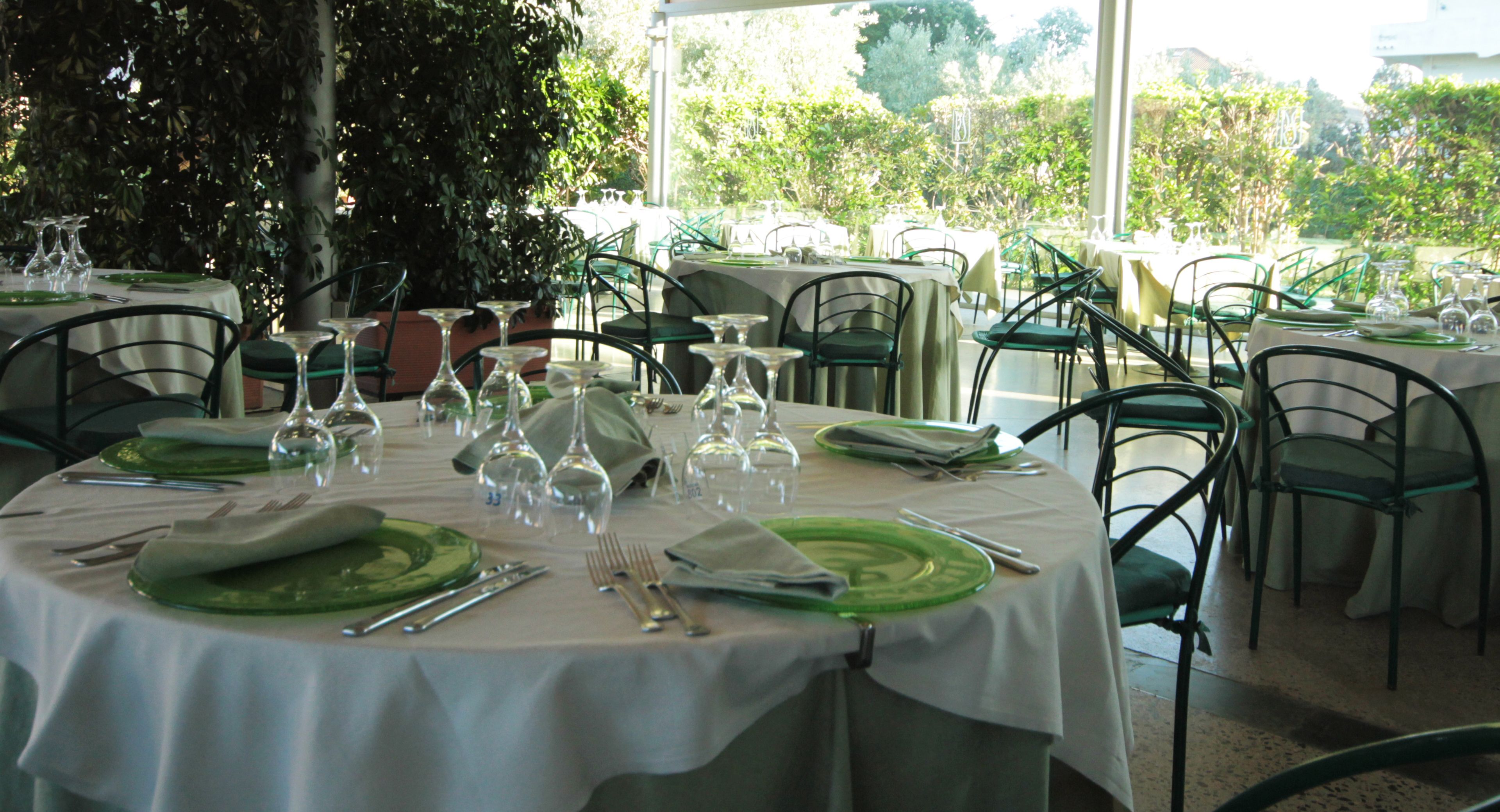 A dining area with round tables set for a meal, surrounded by chairs.