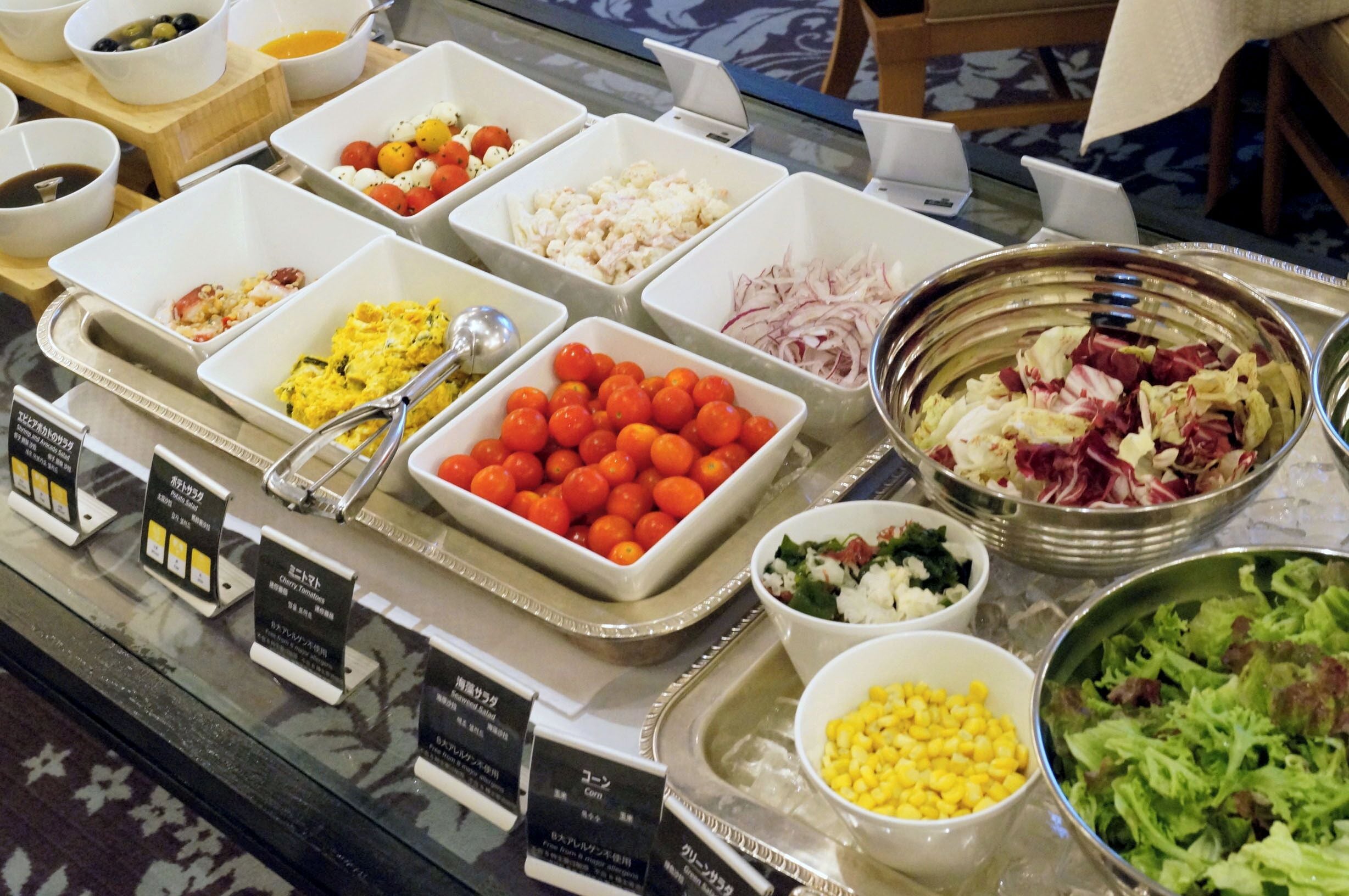 A buffet with various food items including tomatoes, corn, and salads.