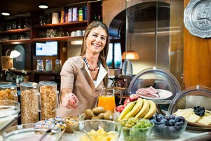 Zona de bufé con diferentes alimentos y una persona atendiendo.