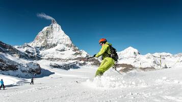 Een persoon skiet een sneeuwhelling af, met een berg op de achtergrond.