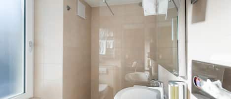 A bathroom with a shower, toilet, sink, and a mirror.