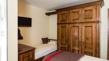 Una camera da letto con un letto singolo, un armadio in legno e una televisione fissata al muro.