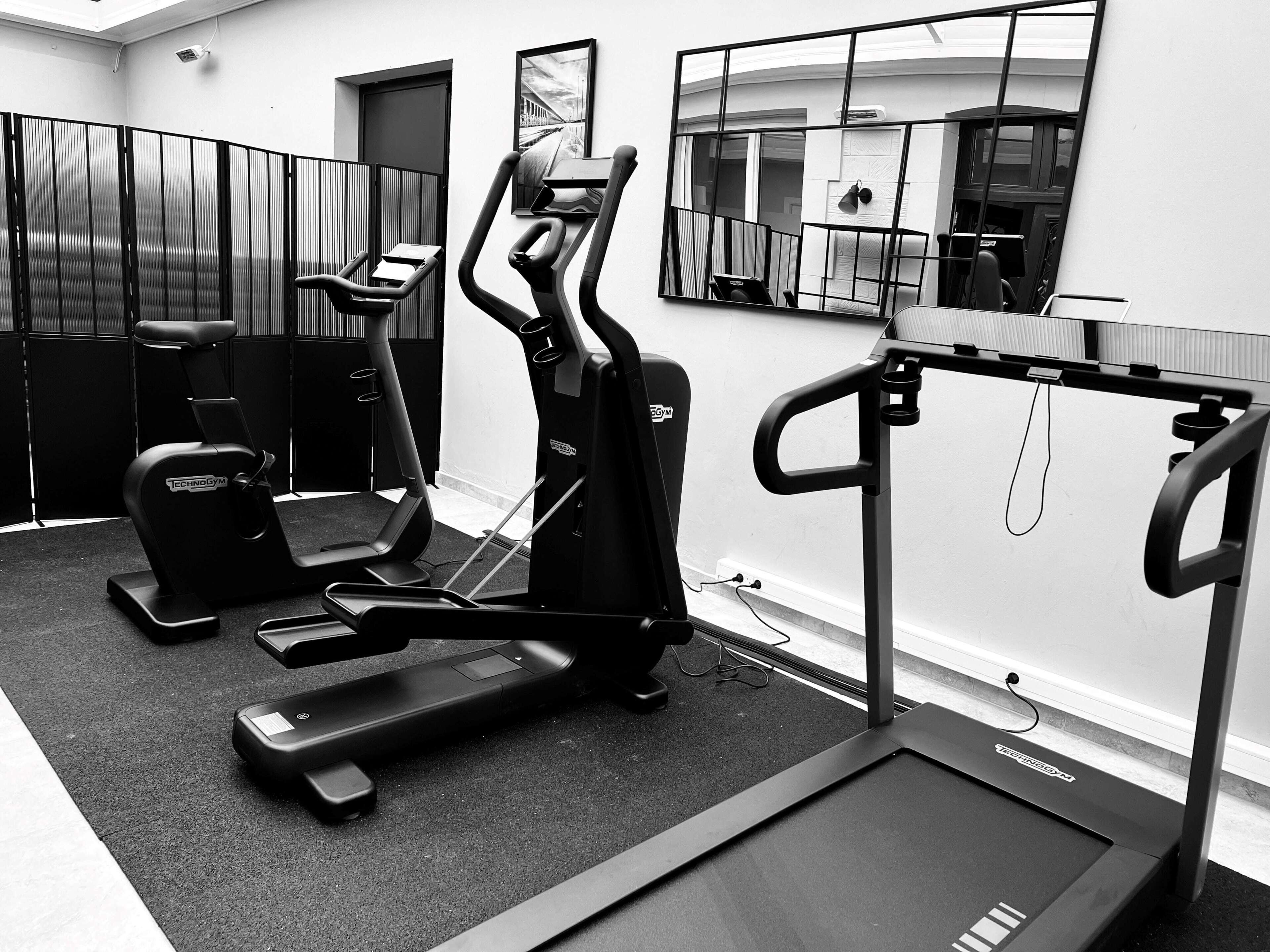 Une salle de sport équipée de vélos d’appartement, d’un tapis de course et d’autres appareils d’exercice.