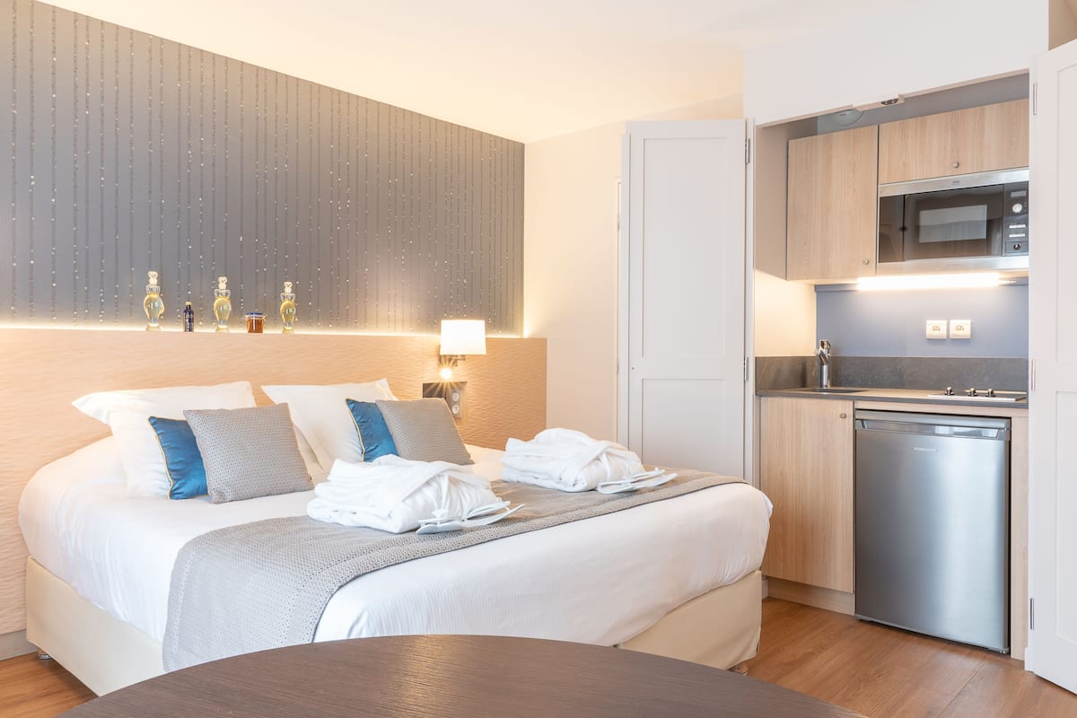 Ett hotellrum med en säng, ett nattduksbord och ett inbyggt köksutrymme med mikrovågsugn och diskmaskin.