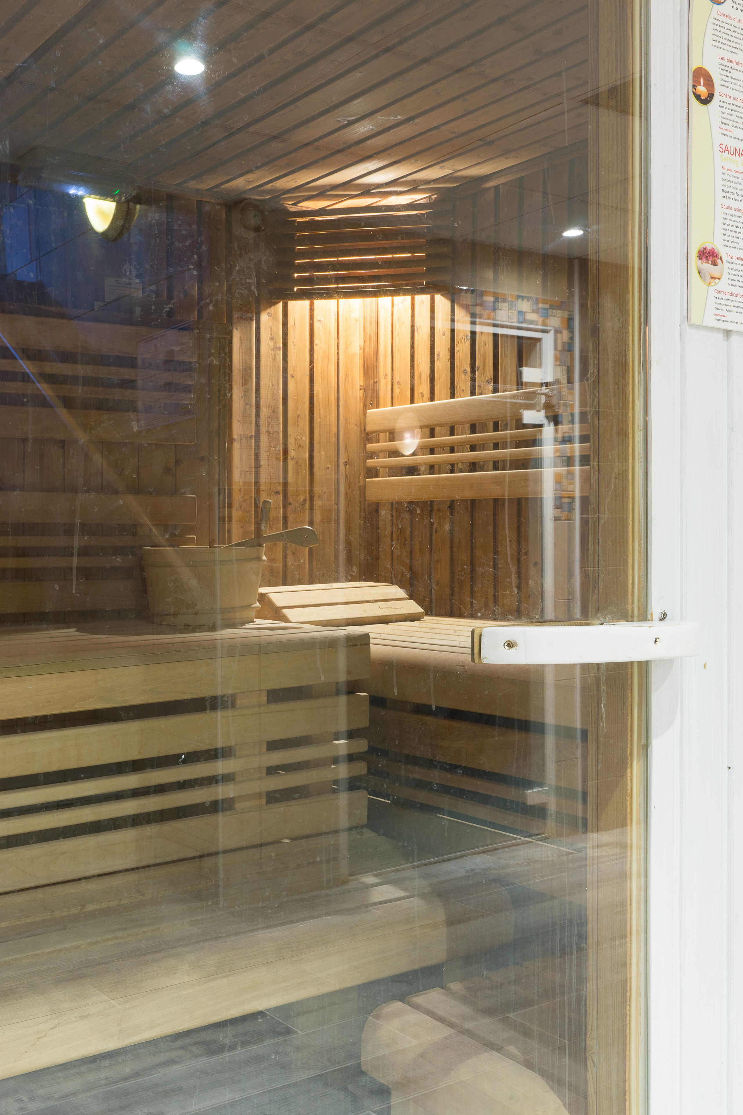 A sauna room with wooden benches and a bench with a footrest.
