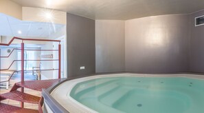 Ein Schwimmbecken mit einer gefliesten Terrasse und einer Treppe, die zu einer erhöhten Ebene führt.