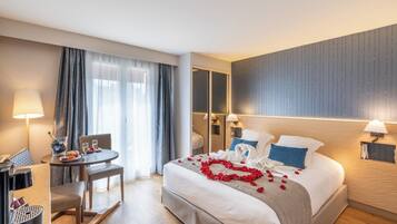 Una habitación de hotel con cama, escritorio, silla, lámpara y espejo.