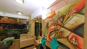 Un hall d’entrée avec un canapé, une table basse et un grand tableau abstrait accroché au mur.