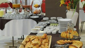 Une table de buffet proposant divers plats, notamment des pâtisseries et du pain, ainsi qu’un coin café avec de nombreuses tasses et une cafetière.