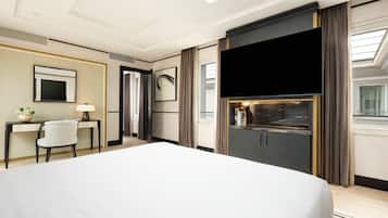 Camera d'albergo con un letto grande, una scrivania con sedia, una TV a schermo piatto e un minibar.
