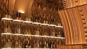 A bar area with shelves of liquor bottles and a curved wall design. - Nobu Hotel Roma (Rome)