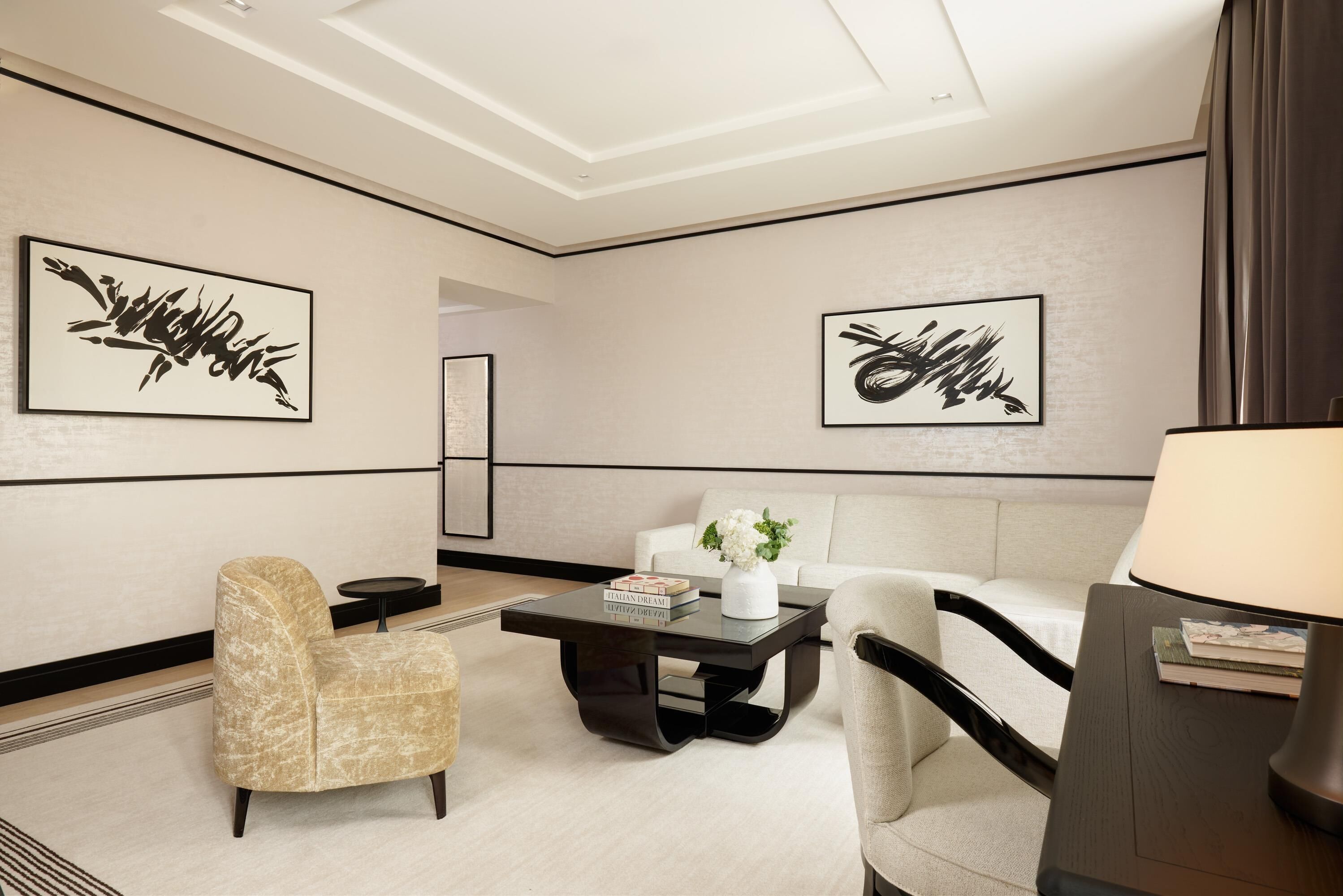 A modern lounge area with a sofa, armchairs, a coffee table, and artwork on the walls.
