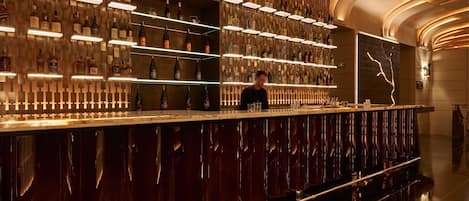 A bar with shelves of bottles and a person standing behind the counter.
