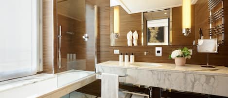 Un baño moderno con ducha de vidrio, un espejo grande y tocador de mármol.