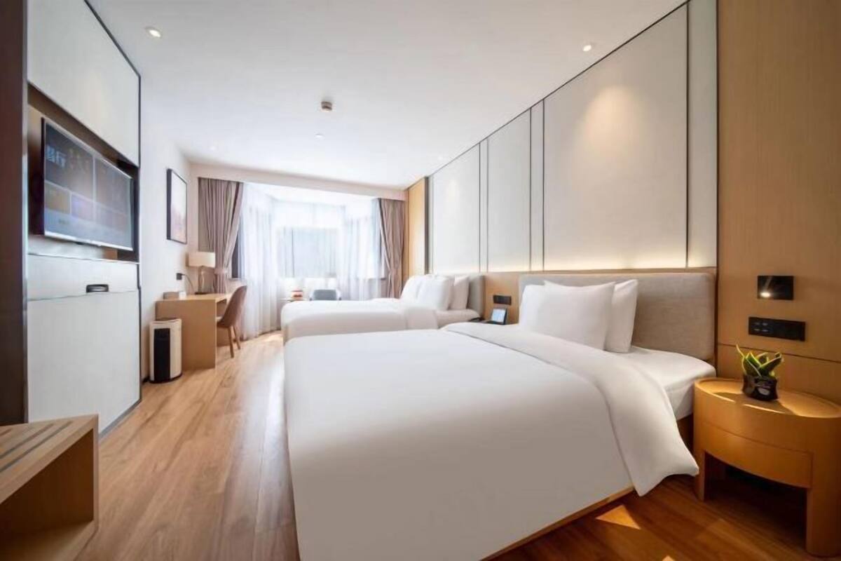 Ein modernes Hotelzimmer mit zwei Betten, einem Schreibtisch und einem Fernseher.