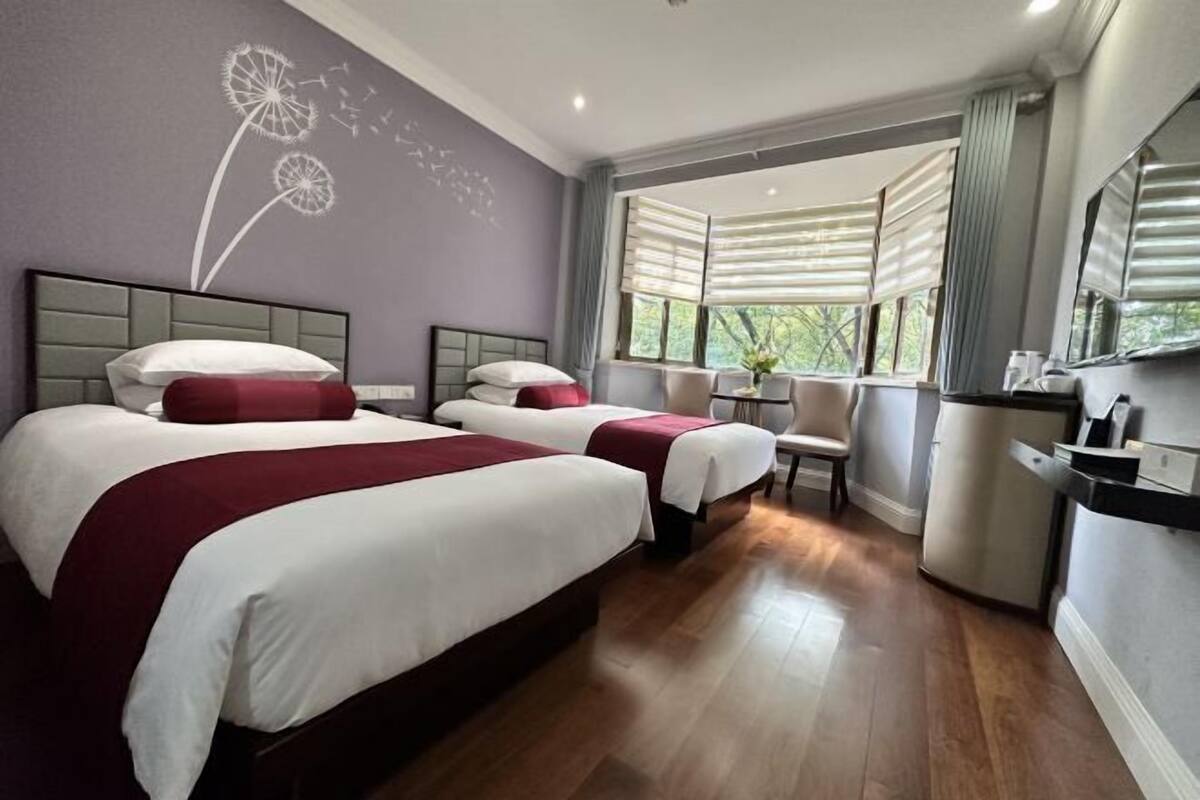 Ein Hotelzimmer mit zwei Betten, einem Schreibtisch und einem Fenster mit Vorhängen.
