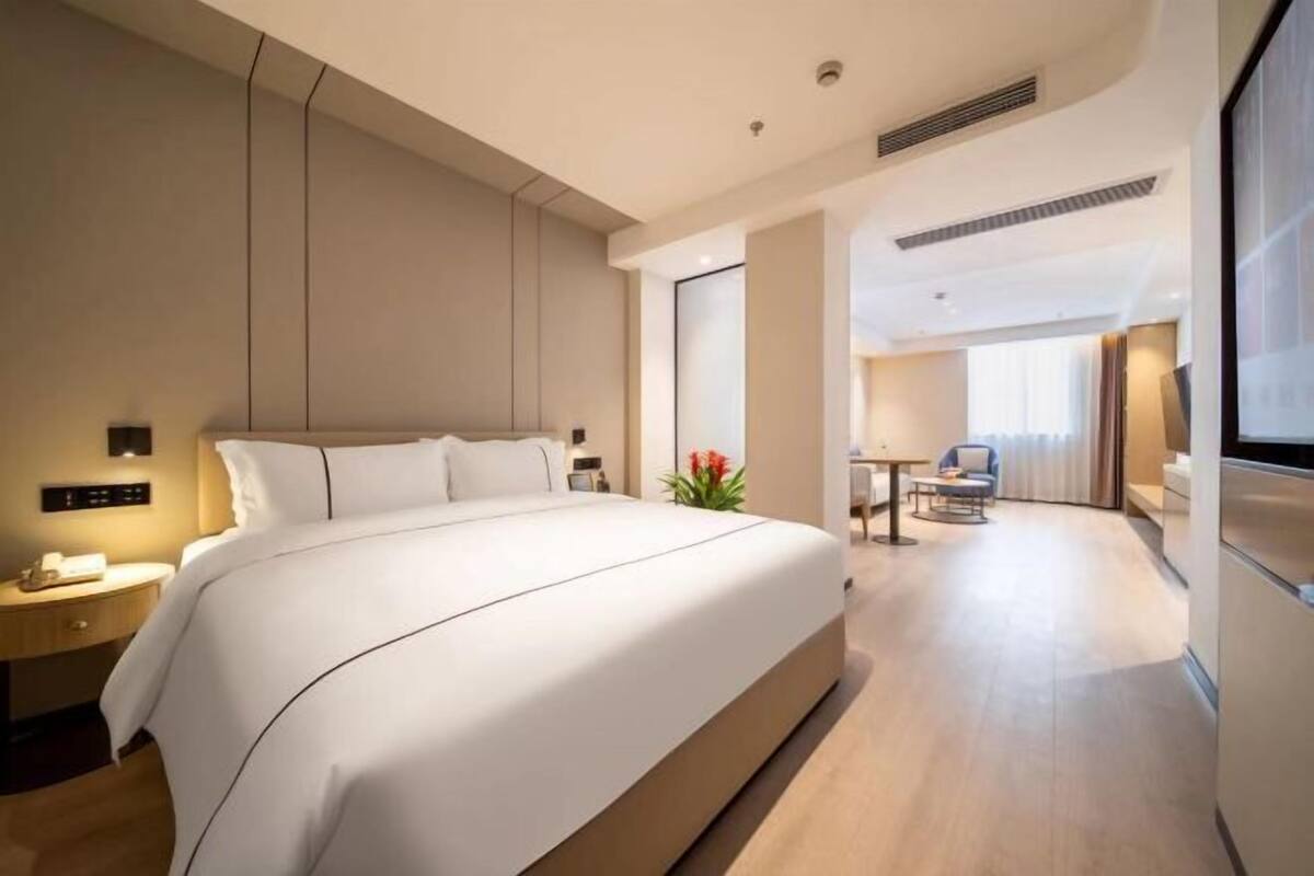 Ein modernes Hotelzimmer mit einem großen Bett, einem Nachttisch, einem Schreibtisch und einem Sessel.