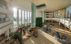 A multi-level atrium with high ceilings, large windows, and a central green wall.