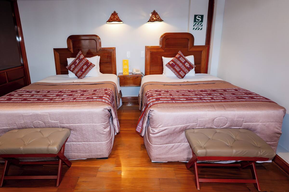 A double room with two beds, bedside tables, and a telephone.