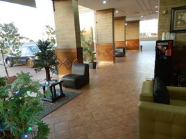 Un vestíbulo con mostrador de recepción, zona de estar y máquina de café Nescafé.