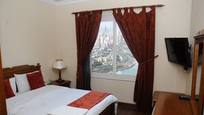 Habitación de hotel con una cama grande, un televisor y vistas a la ciudad a través de la ventana.