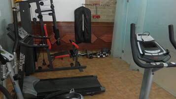 Un gimnasio en casa con cinta de correr, elíptica y banco de pesas.