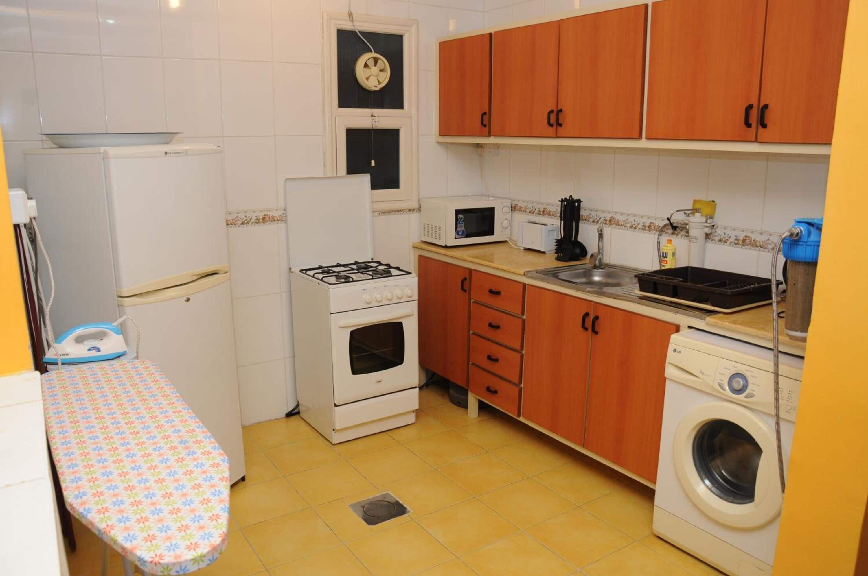 Une cuisine compacte équipée d’une cuisinière à gaz, d’un four à micro-ondes, d’un évier et d’un lave-linge.