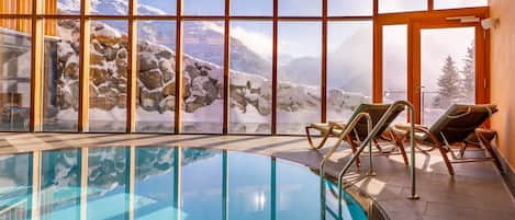 Una piscina techada, una piscina al aire libre, sombrillas