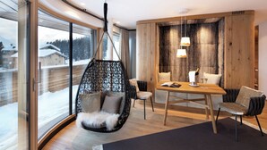 Un interior moderno con un ventanal grande, una silla colgante, una mesa de comedor con sillas y una pared de acento de madera.