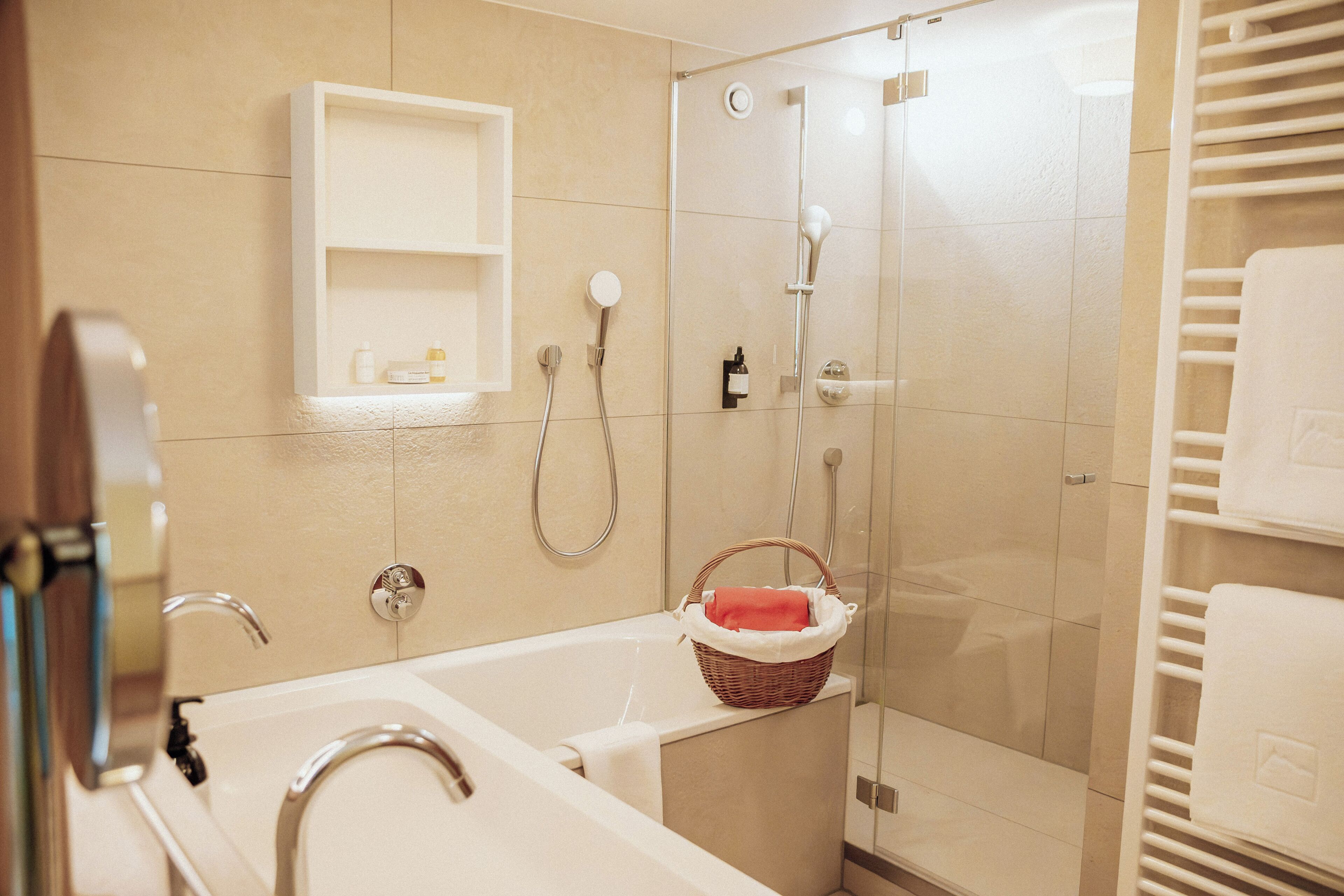 Ein modernes Badezimmer mit Badewanne, einer Glastrennwand-Dusche und einem weißen Handtuchhalter.