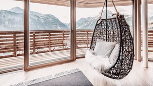 Una habitación con ventanas amplias, una silla colgante y vistas a montañas.