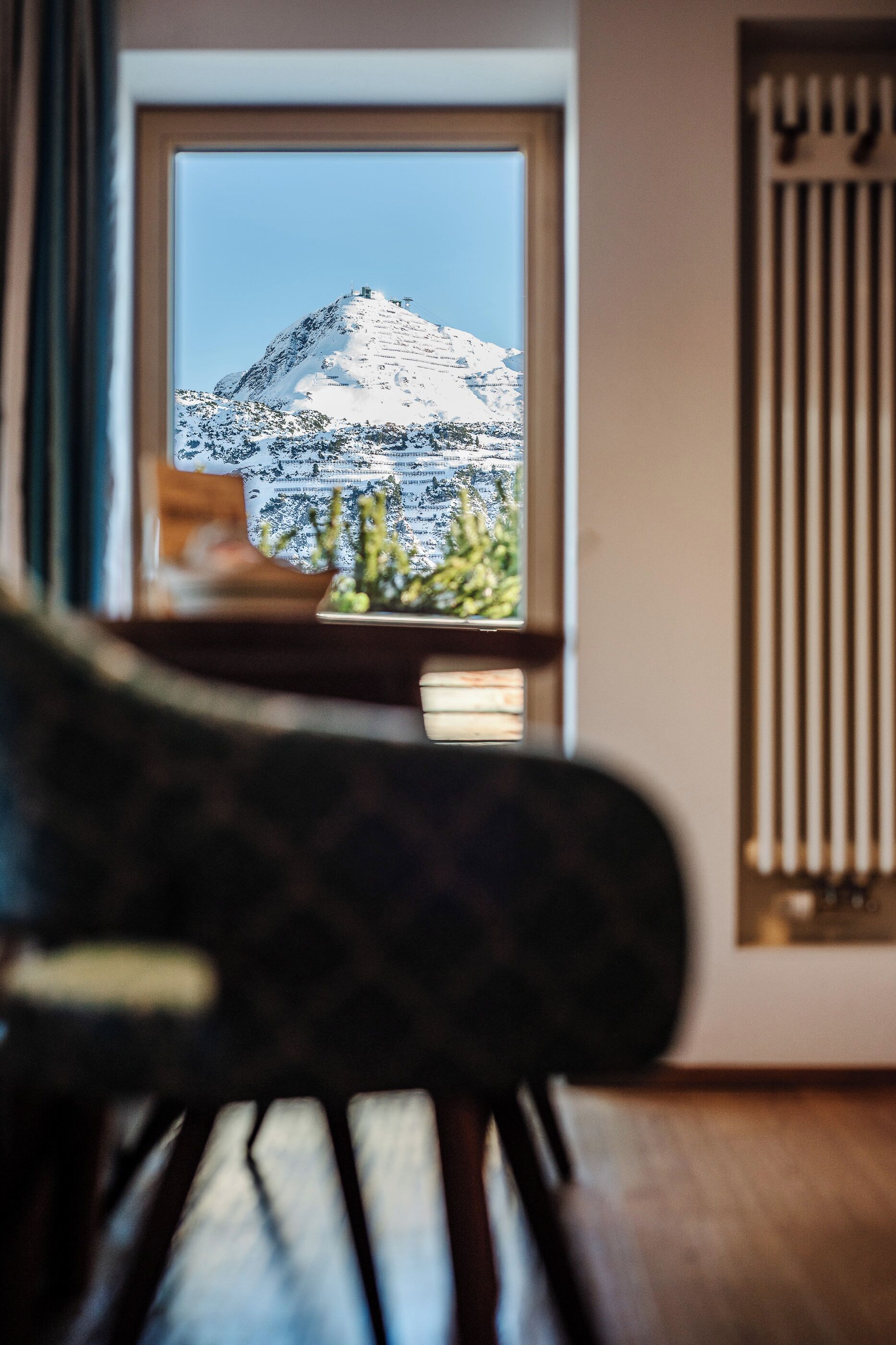 Una habitación con vista a una montaña nevada, una ventana y un radiador.