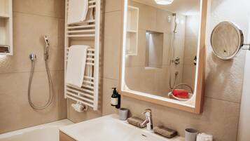 A modern bathroom with a bathtub, a sink, a mirror, a towel rack, and a shower.