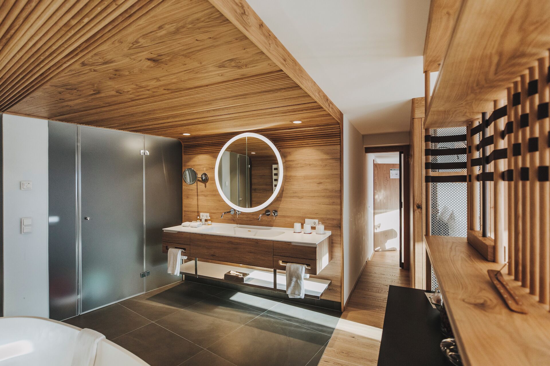 Un baño moderno con techo de madera, un espejo grande y un mueble de tocador doble.