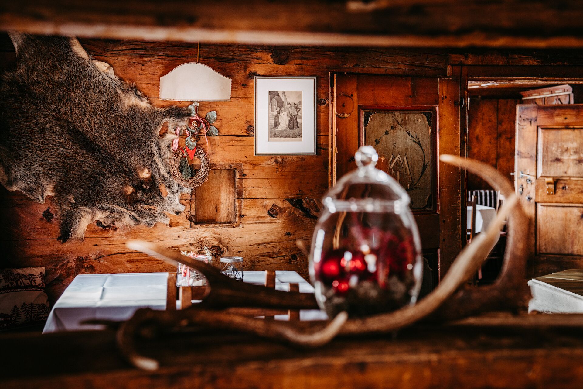 Una habitación rústica con paredes de madera, un cuadro enmarcado, una lámpara y un tarro de vidrio con contenido rojo.