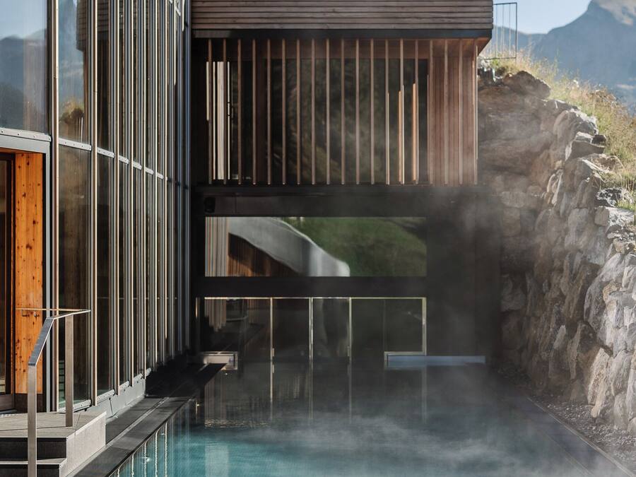 A modern building with a pool, wooden slats, and a stone wall.