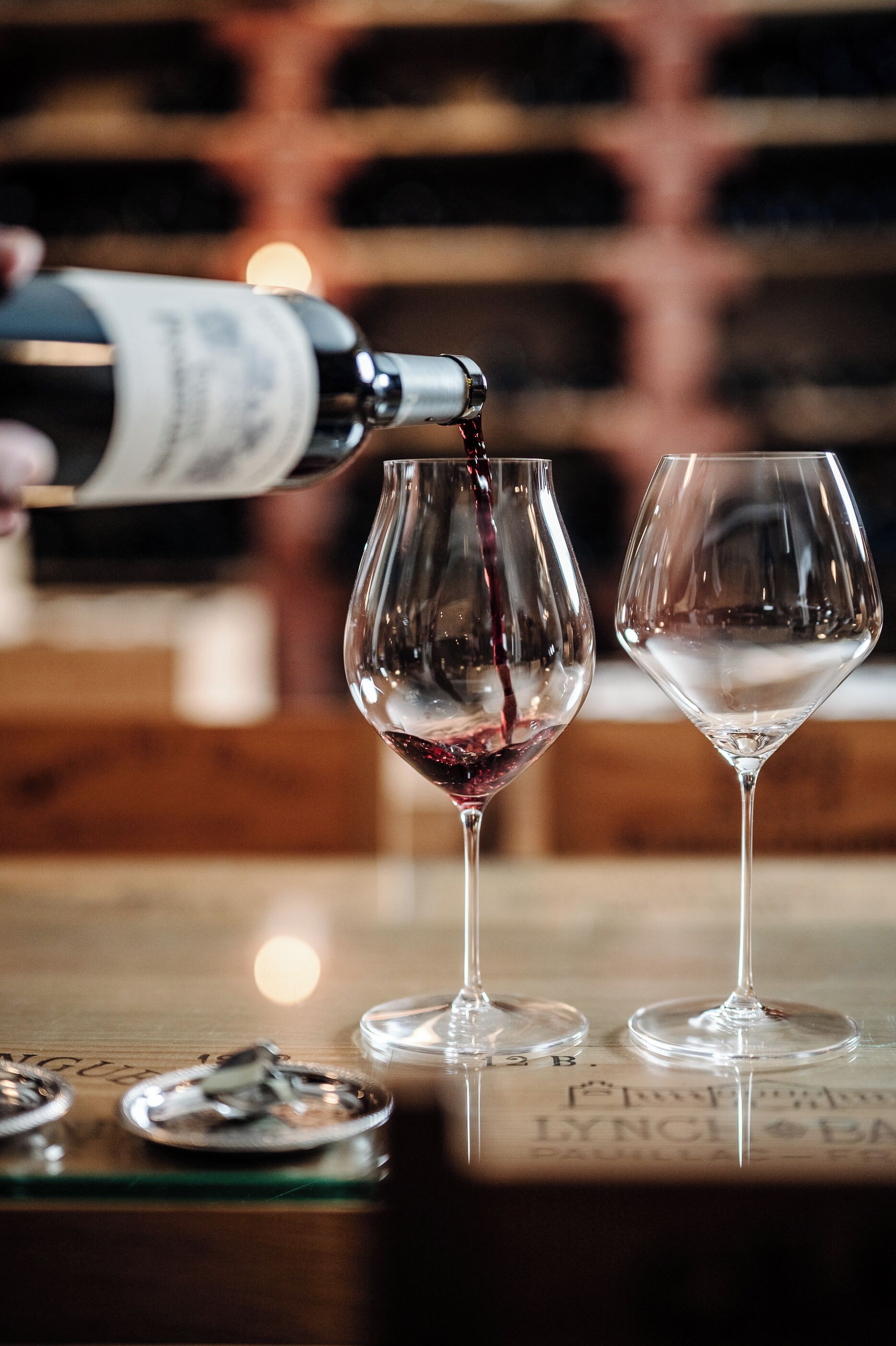 Une bouteille de vin est versée dans un verre, et un autre verre vide se trouve à côté.