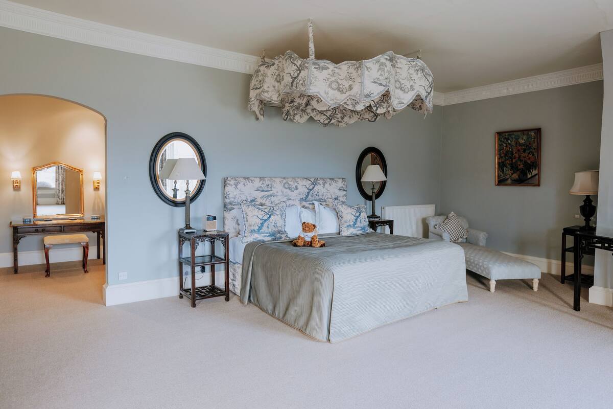 A bedroom with a large bed, a desk, a chair, and a nightstand.