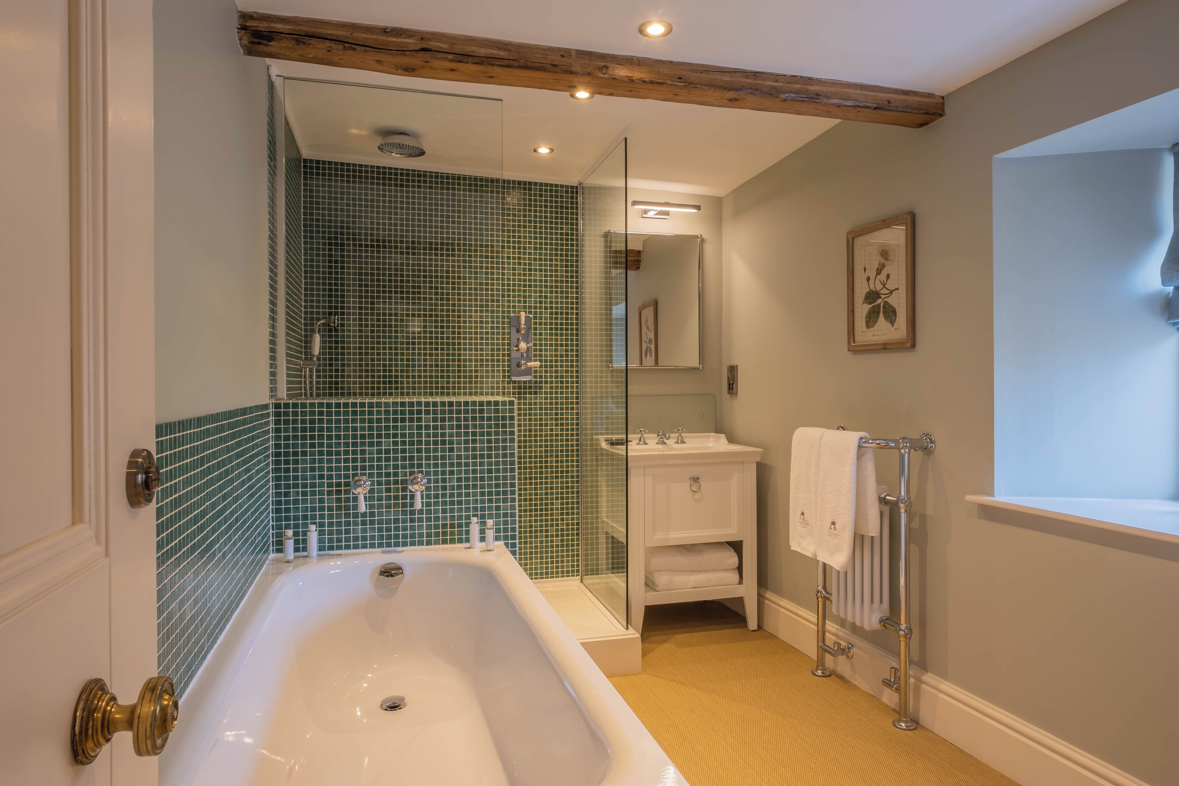 A bathroom with a bathtub, a glass shower enclosure, a sink, and a mirror.
