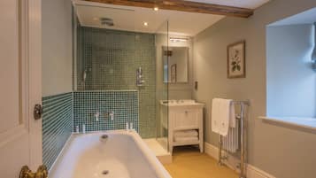 A bathroom with a bathtub, a glass shower enclosure, a sink, and a mirror.