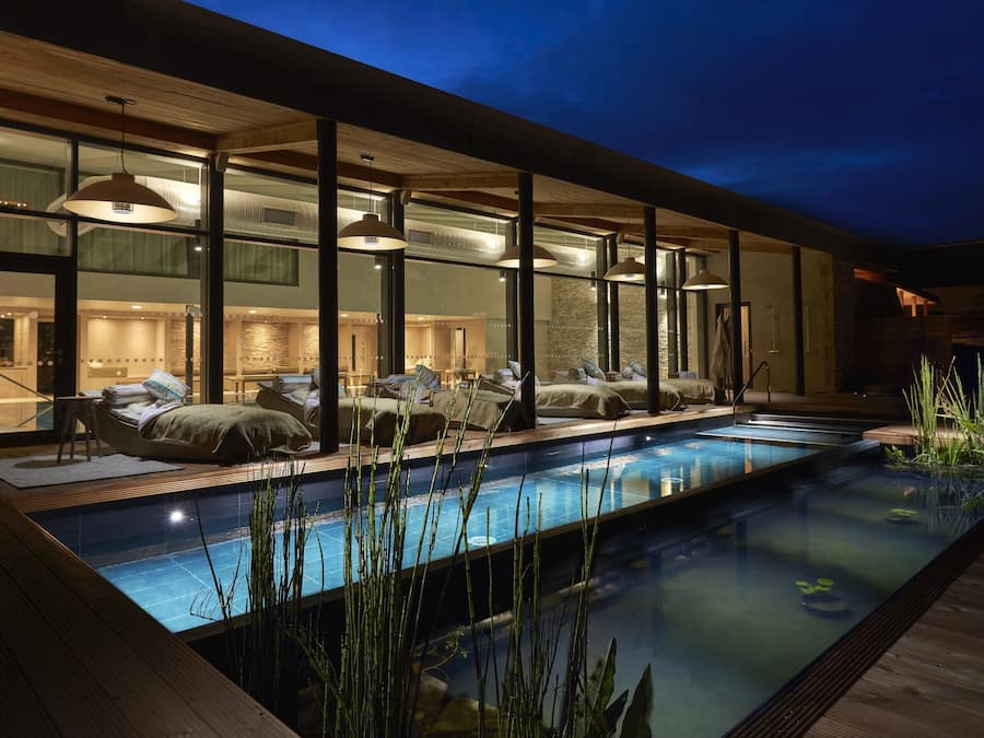 Een binnenzwembad, een buitenzwembad, ligstoelen bij het zwembad